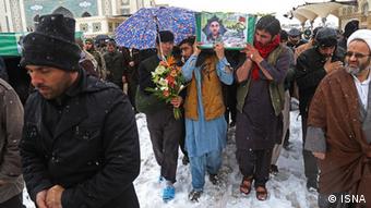تصویر مهاجران افغان در مراسم تشییع جنازه. دو نفر از آنها یکی در هوای برفی صندل تابستانی به پا دارد و دیگری پلاستک به پا کشیده و دمپایی پا کرده است.